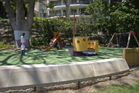 Mother and child watch toddler go down slide at Beare Park Playground