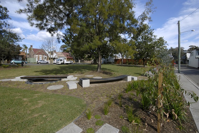 The small playground in the foreground and a large shady tree in the background