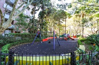 Play equipment in the playground include swings, climbing structure and slide. 