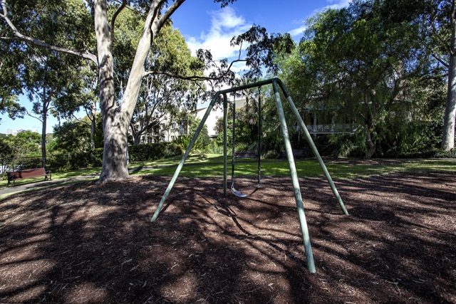 The swing set in a shaded area of Ernest Pedersen Reserve Playground.