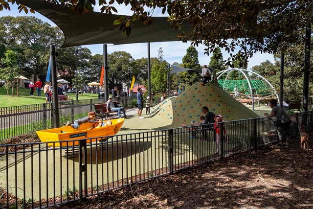 Playground equipment including a boat shaped ride covered with shade sails and surrounded by trees