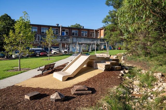 A slide and nature play area, with rocks for balance play.