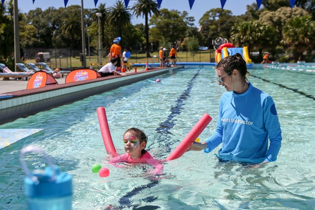 Young girl and a swimming instructor, practicing a swimming exercise.