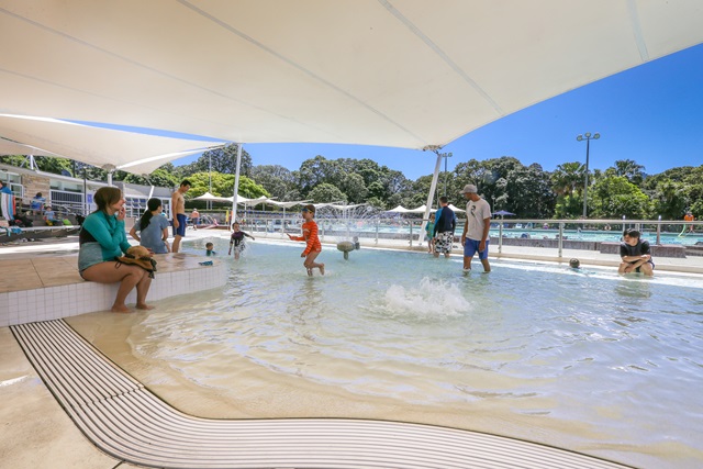 Children playing in the shaded splash pool. 