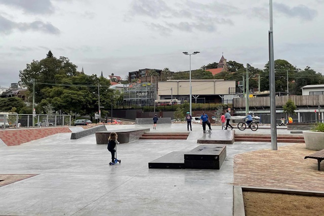 Children playing on skateboards and scooters at a outdoor skate park
