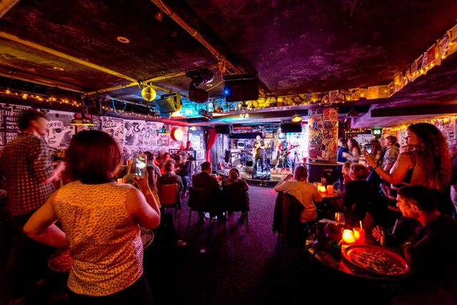 Live band plays music on stage in front of a small audience
