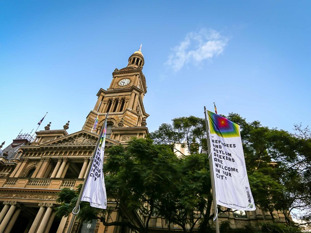Flags with a message welcoming refugees and asylum seekers fly in front of Sydney Town Hall.