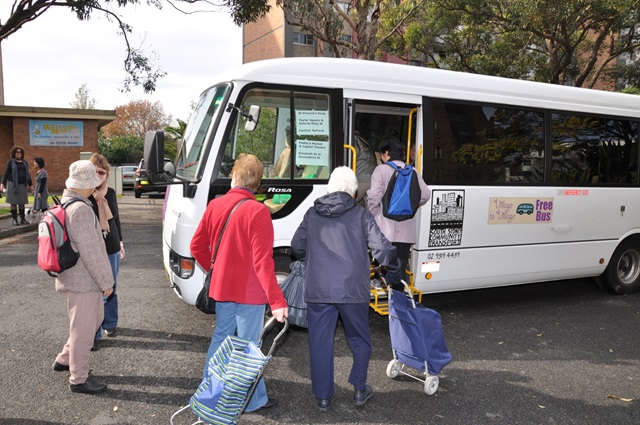 People walking towards a small community bus