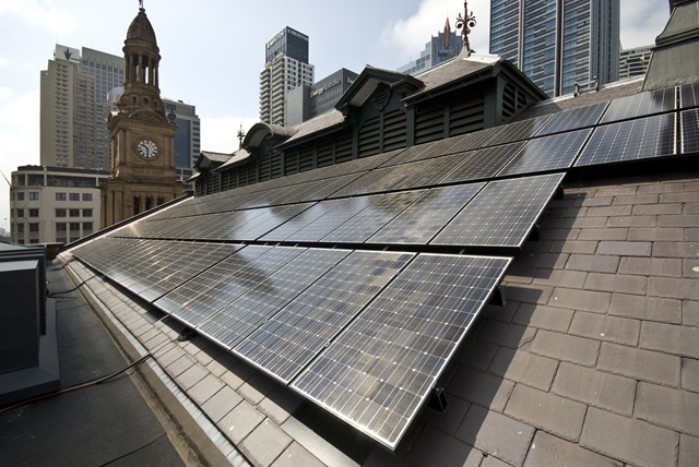 Solar panels on a building roof with the city skyline in the background.
