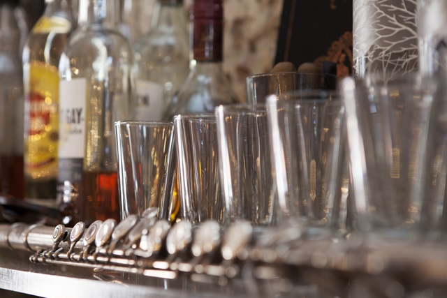 Empty row of glasses next to some alcohol