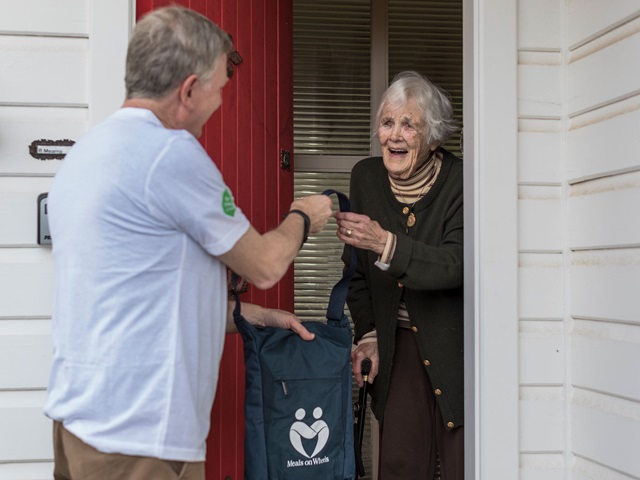 Man delivering food to an elderly woman at her home
