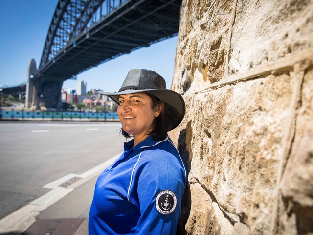 A ranger standing next to a wall with Sydney Harbour Bridge in the background