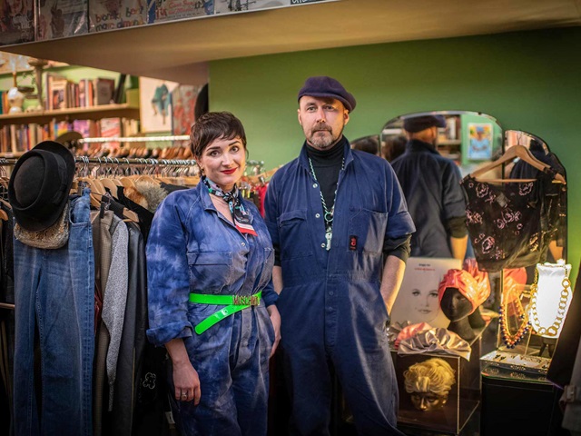 2 people in overalls standing in a shop