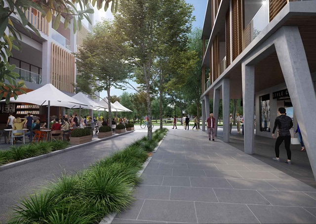 View along a paved pedestrian-friendly street flanked by apartment buildings towards a park.