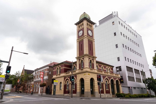 A heritage building with clock tower on the corner of a city street.