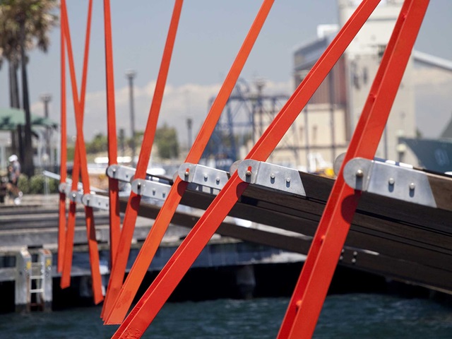 Steel structure and part is painted red, buildings are in the background.