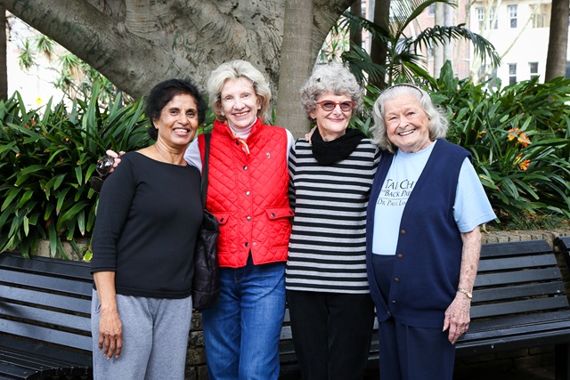 Four people standing in front of a garden