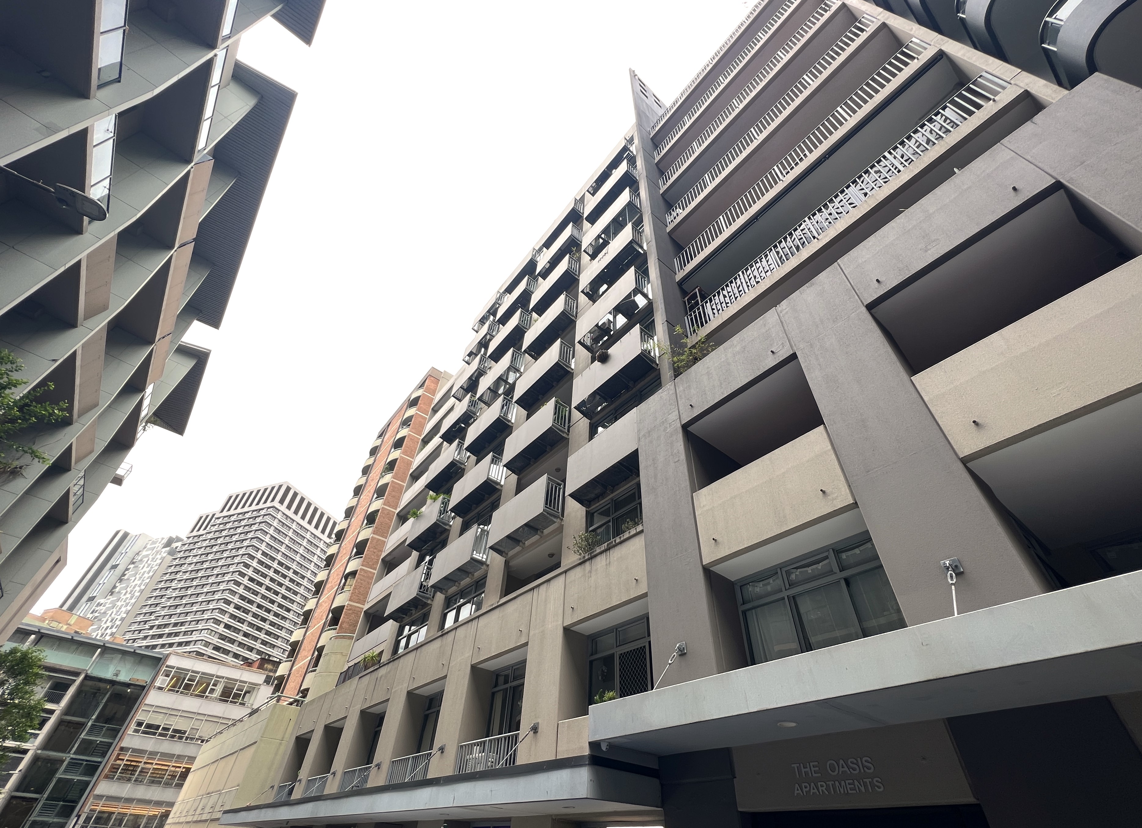  Street view of modern high-rise apartment buildings under a cloudy sky.