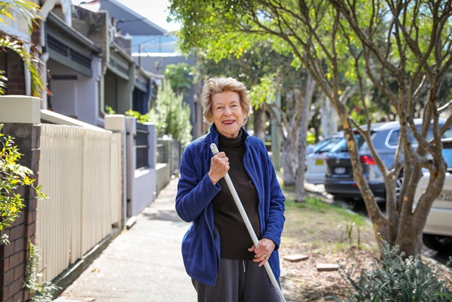 Woman with white cane on suburban street