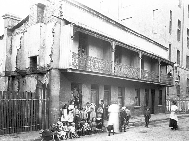 Photo from the early 1900s of a terrace house with children and women outside.