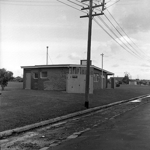 An historic photo of a street view with powerlines and a building.