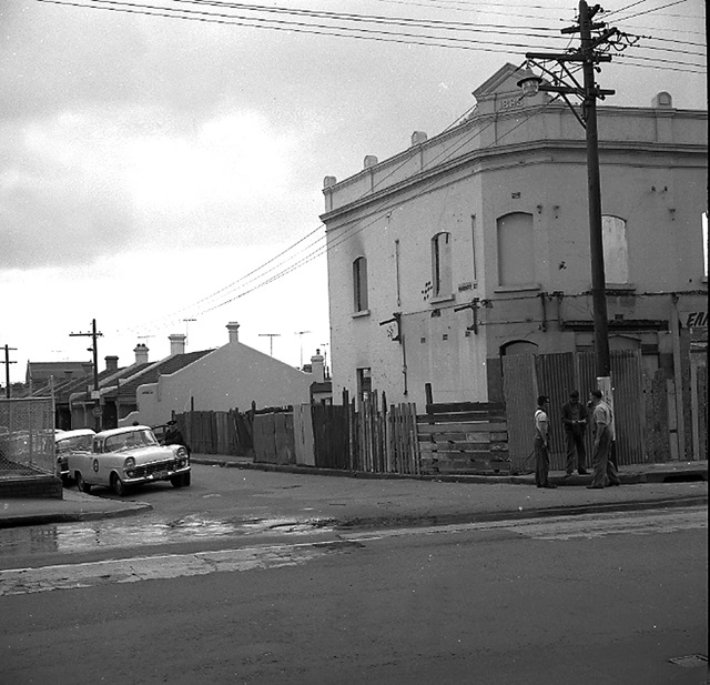 An historic photo of a road with a car and building.