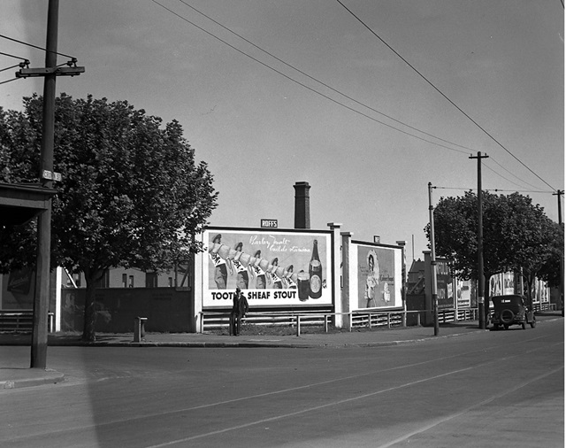 An historic photo of a street view and big billboards in the distance.