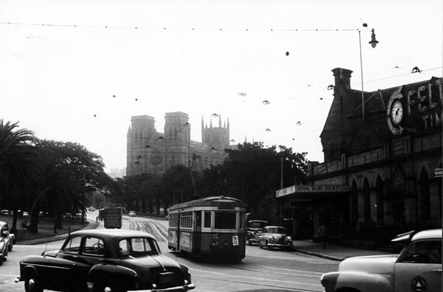 An historic photo of a street with cars and buildings.