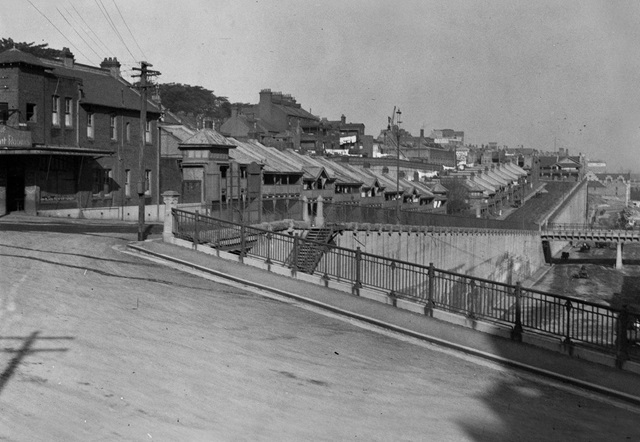 An historic photo of a road with houses in the distance.