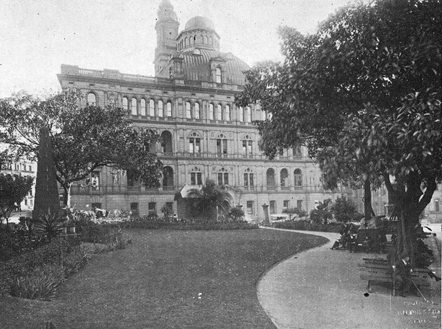 An historic photo with grass and pathway leading to multi-storey building, and trees either side.