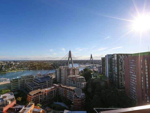 View from a top floor to other apartment buildings alongside Sydney harbour, an arm of which is crossed by the Anzac Bridge.