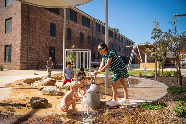 Children play in a water feature in an urban park.