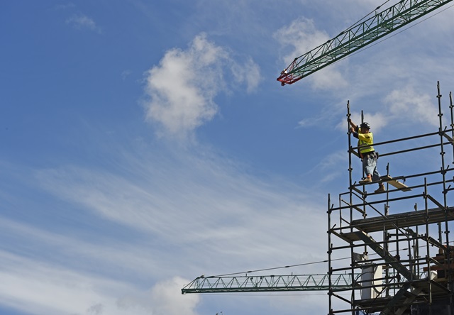 Person on scaffolding with crane overhead