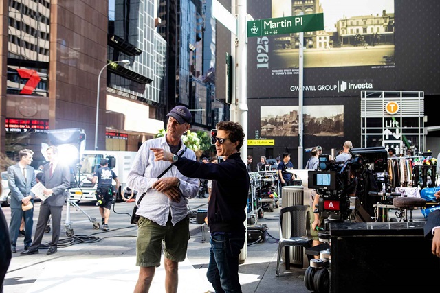Film production on a city street, showing actors, crew and film equipment.