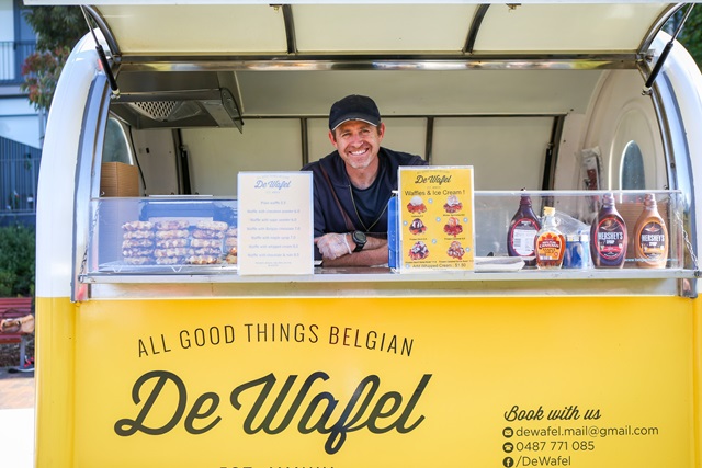 A man inside a yellow mobile food vending van.