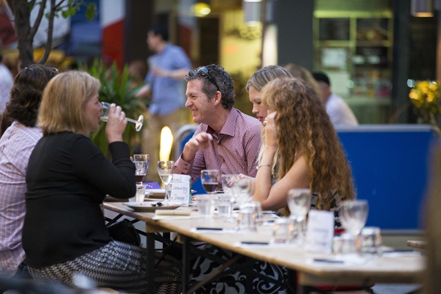 A group of adults sitting at an outdoor dining table.