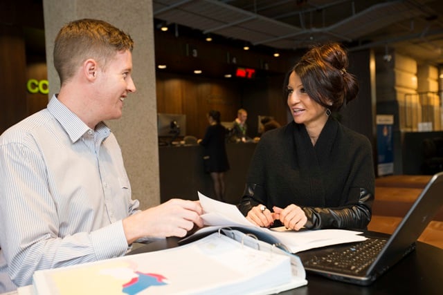 Two people talking with paperwork at a desk