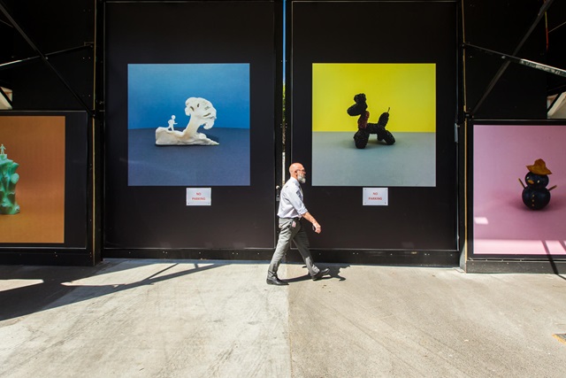 Man walking in front of colourful pictures.