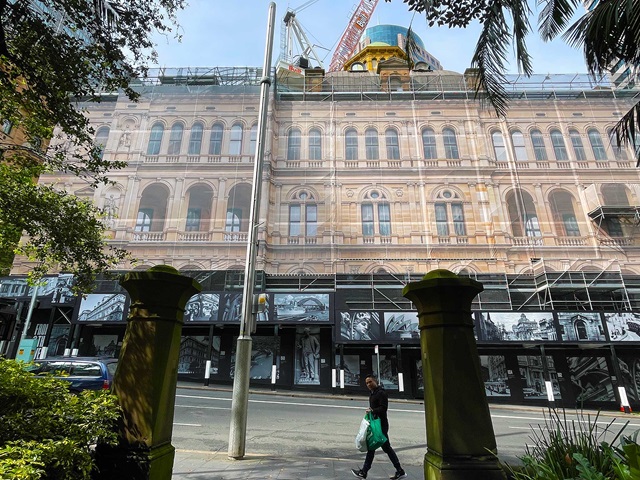 City street with a heritage building being renovated. The facade is printed on the scaffolding cover.