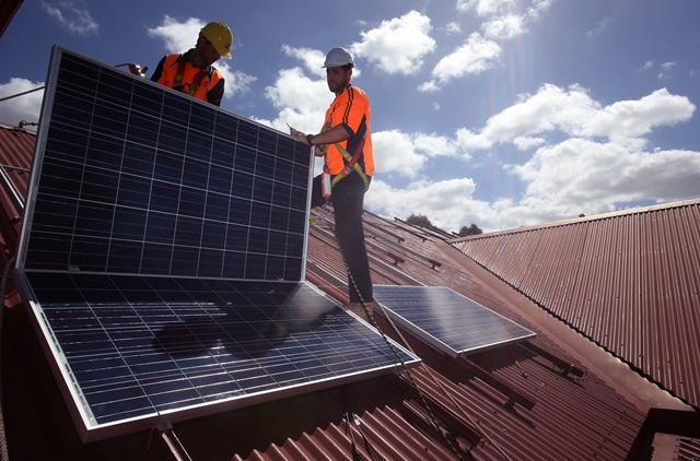 Workers installing solar panels on a roof.