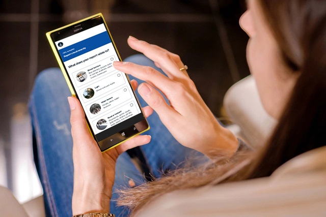 A person uses a smart phone to fill out a form to report an issue.
