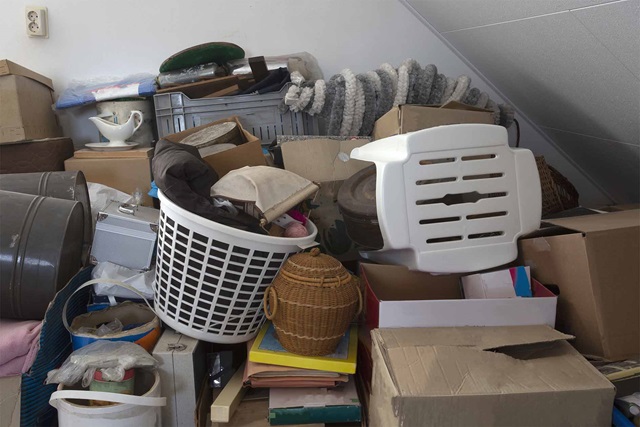 Chairs, baskets, boxes and other items are stacked on top of each other in a crowded room.