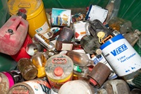 A pile of old tins and plastic containers filled with household chemicals.